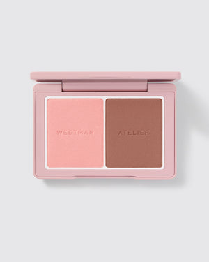 A compact powder blush duo by Westman Atelier, with one shade darker and one lighter, housed in a pink case.