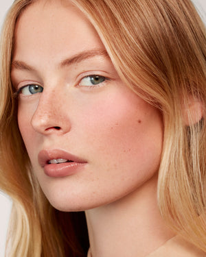 Close-up of a person with blonde hair and freckles on a neutral background
