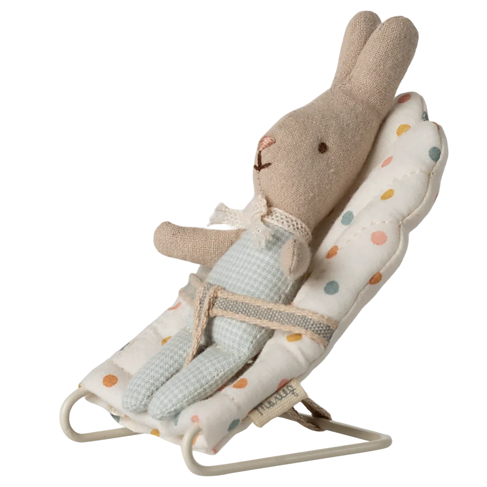 Stuffed rabbit toy in a baby bouncer with a white background