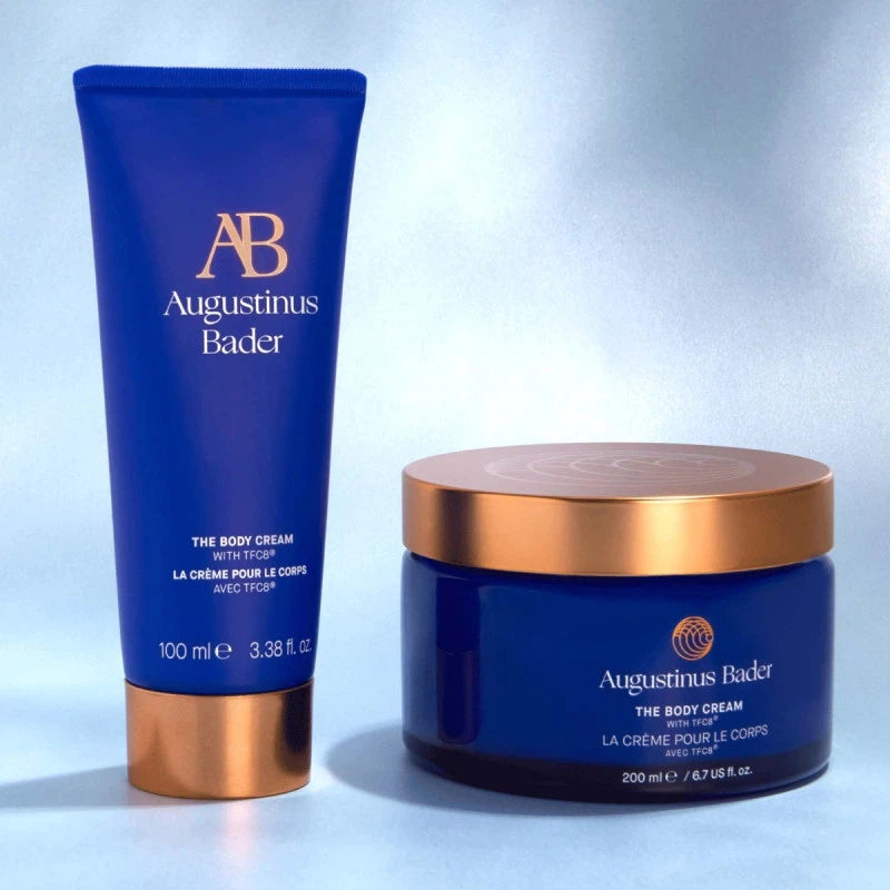 Two Augustinus Bader body cream products on a light gray background
