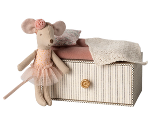 A toy mouse with a pink dress and flower decoration sitting on top of a daybed.
