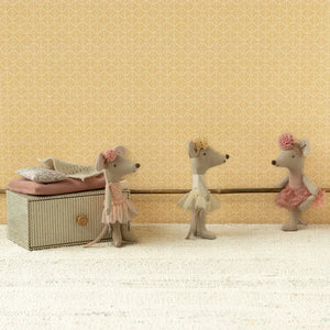 Three toy mice in ballet costumes on a beige surface with a patterned wall in the background