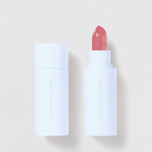 Lipstick with white casing and red shade on a light beige background
