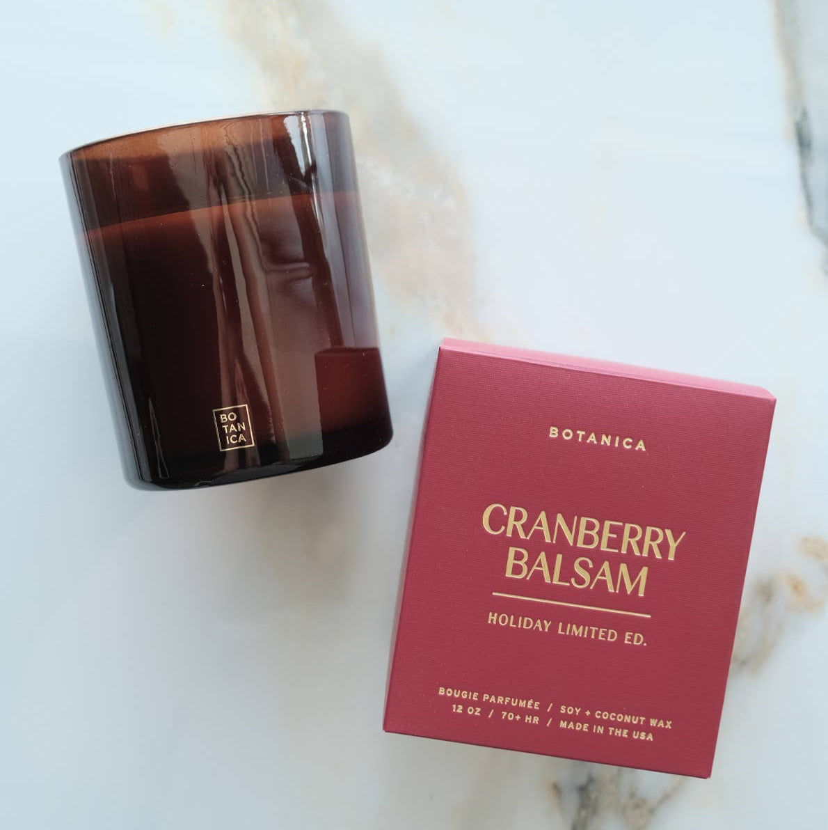 Cranberry Balsam candle and its packaging on a gray background