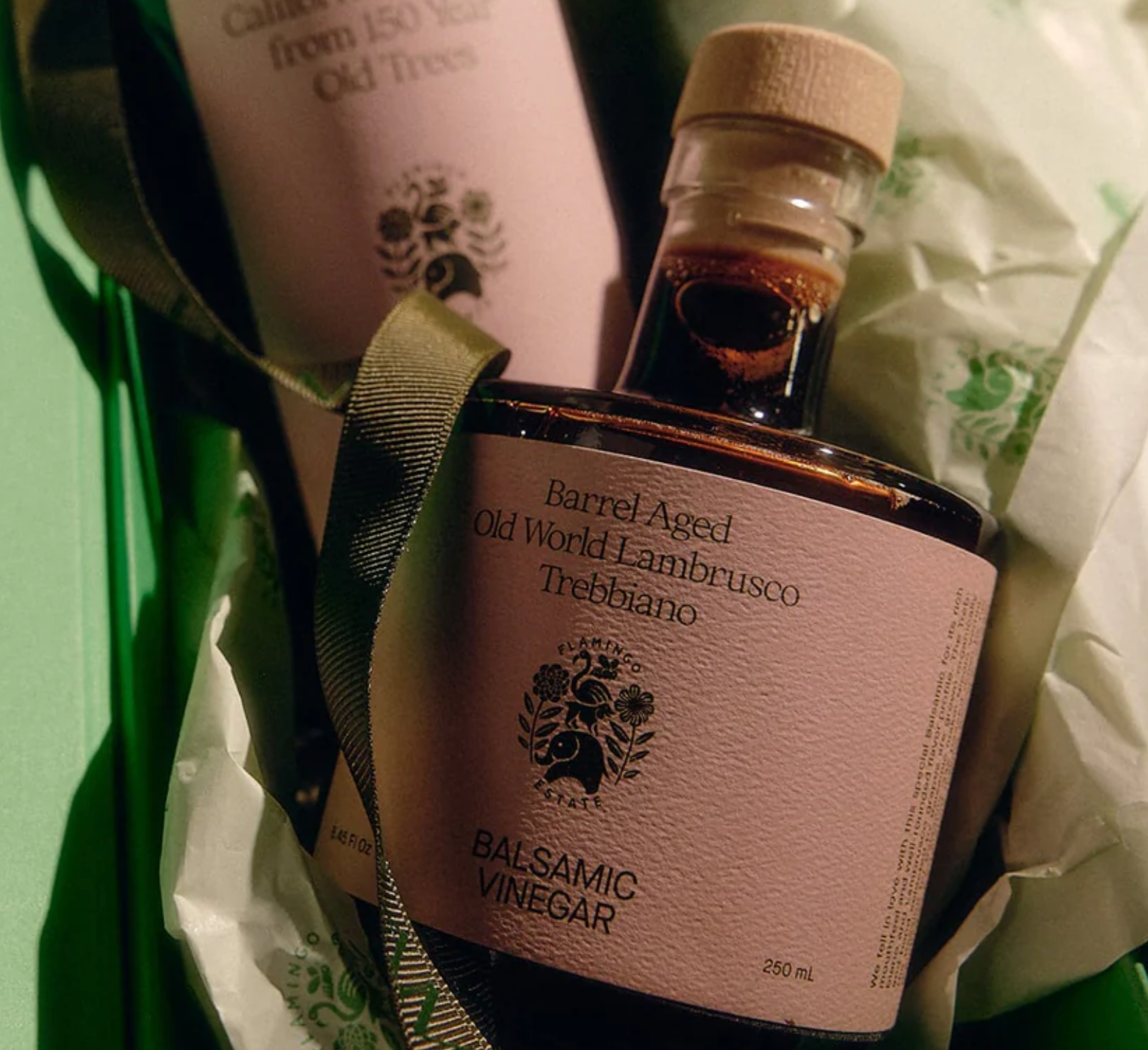 A bottle of Flamingo Estate barrel aged balsamic vinegar with green paper and ribbon