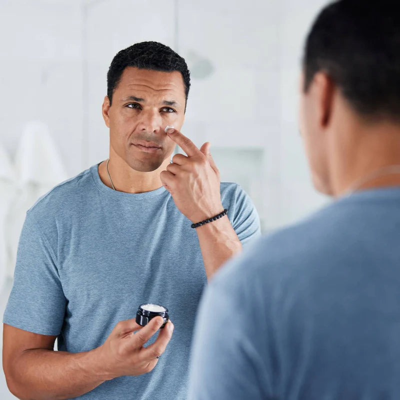 A man applying moisturizer to his fce. 