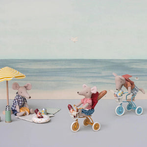 Toy mice and mice with bicycles and beach umbrella on a plain background.