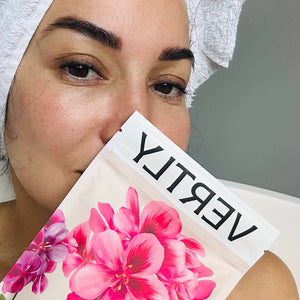 Woman holding a floral product packaging with 'VERITY' branding.