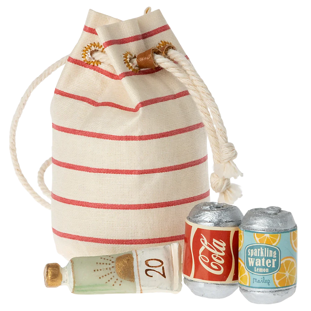 A small, striped beige and red toy beach bag with a green and yellow miniature sunscreen bottle and two miniature soda cans.