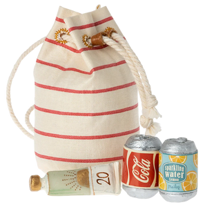 A small, striped beige and red toy beach bag with a green and yellow miniature sunscreen bottle and two miniature soda cans.