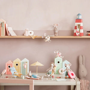 Children's toys and decorations on a shelf and table against a pink wall.