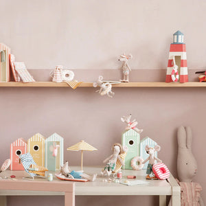Children's toys and decorations on a shelf and table against a pink wall.