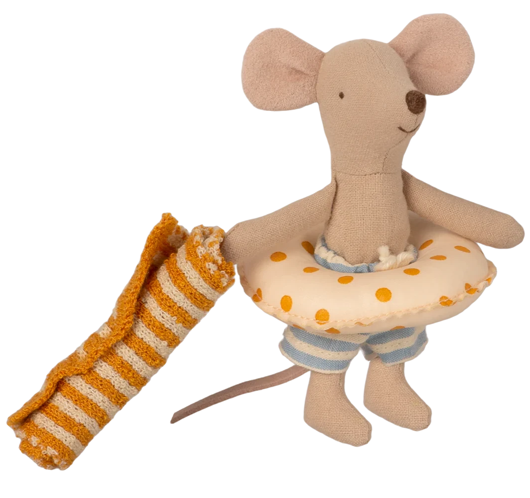 A toy mouse in a beach outfit, holding a float, standing in front of a striped beach house.