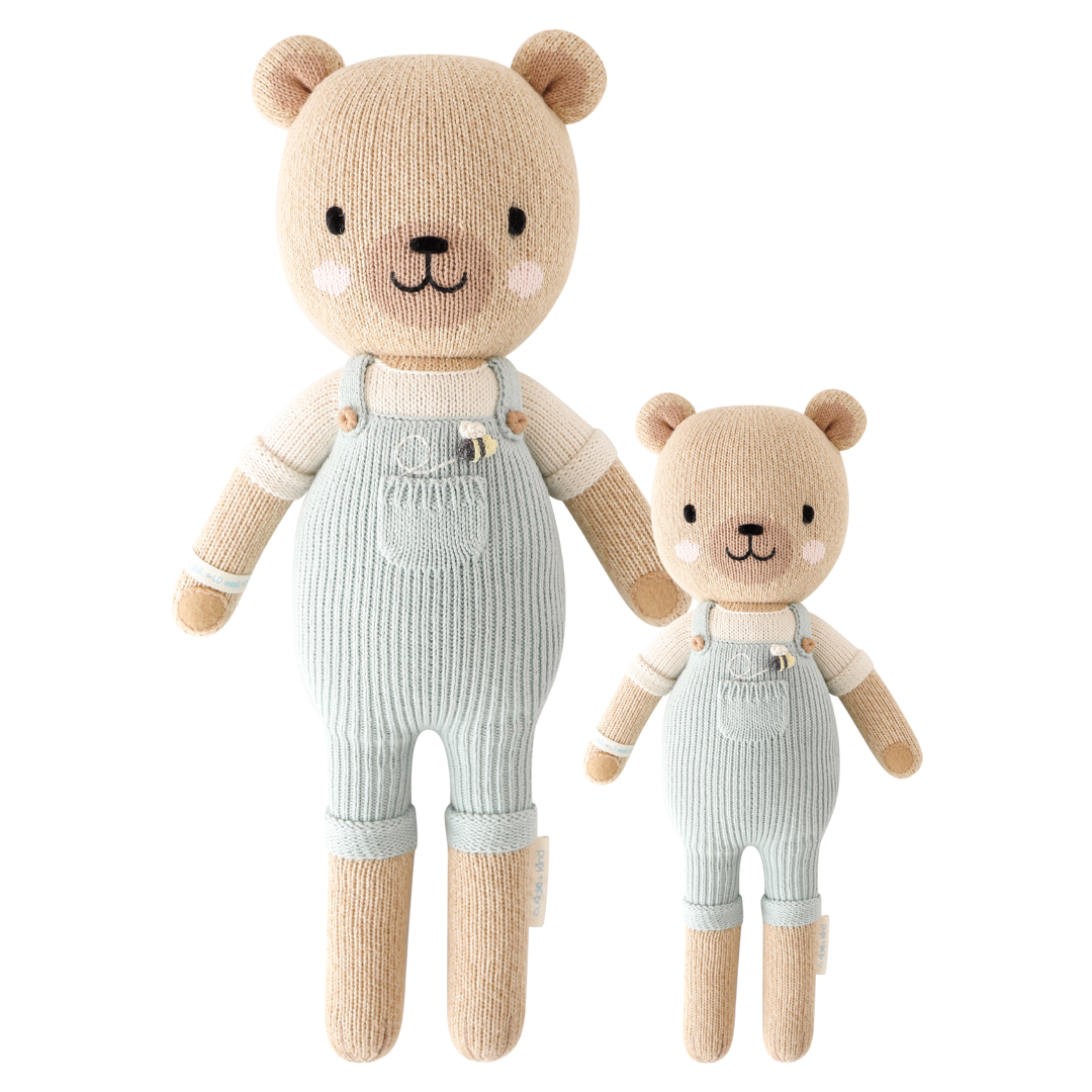 Two hand-knit dolls resembling honey bears, one larger and one smaller, in striped overalls. They are beige, white, and blue in color.
