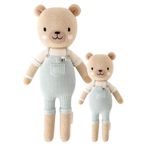 Two hand-knit dolls resembling honey bears, one larger and one smaller, in striped overalls. They are beige, white, and blue in color.
