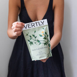 Person holding a VERTLY product package against a neutral background
