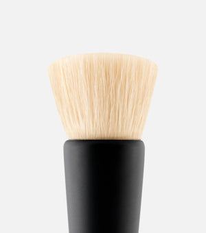 Makeup brush with black handle and beige bristles on a white background