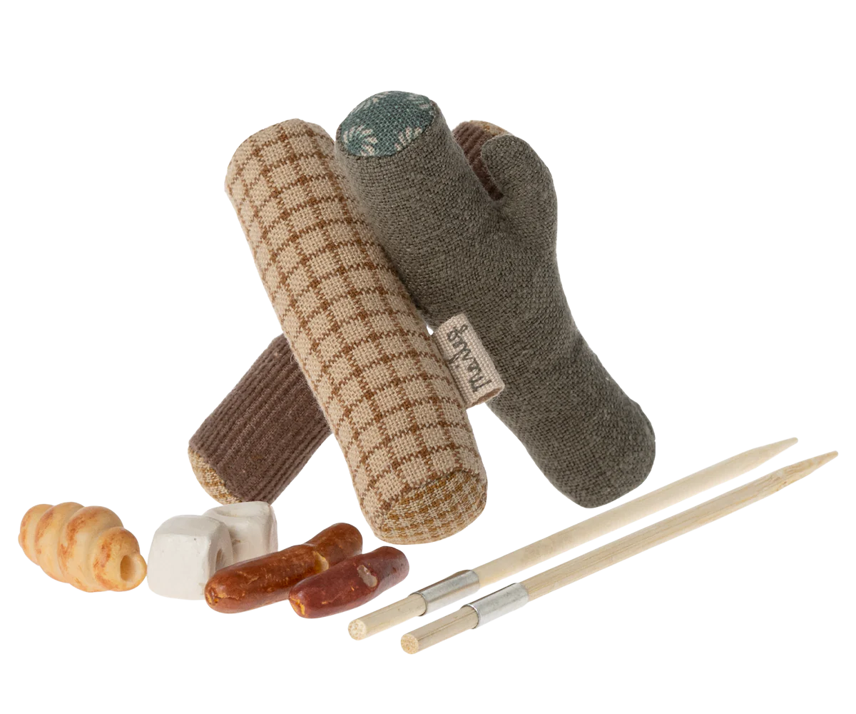 An assortment of toy camping items including a fabric bonfire, sticks, marshmallows, bread, and sausages designed for play with small mouse figures.
