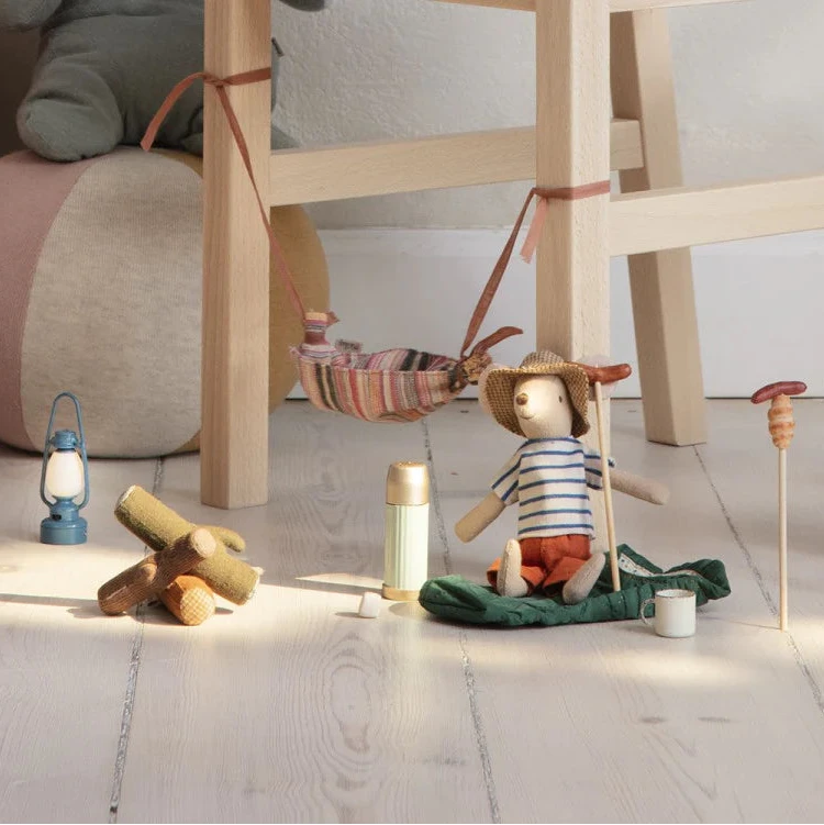 An assortment of toy camping items including a fabric bonfire, sticks, marshmallows, bread, and sausages designed for play with small mouse figures.