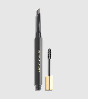 A dual-ended eyebrow pencil with a spoolie brush, labeled 'Westman Atelier Bonne Brow Defining Pencil' with a black body and gold-colored accents.