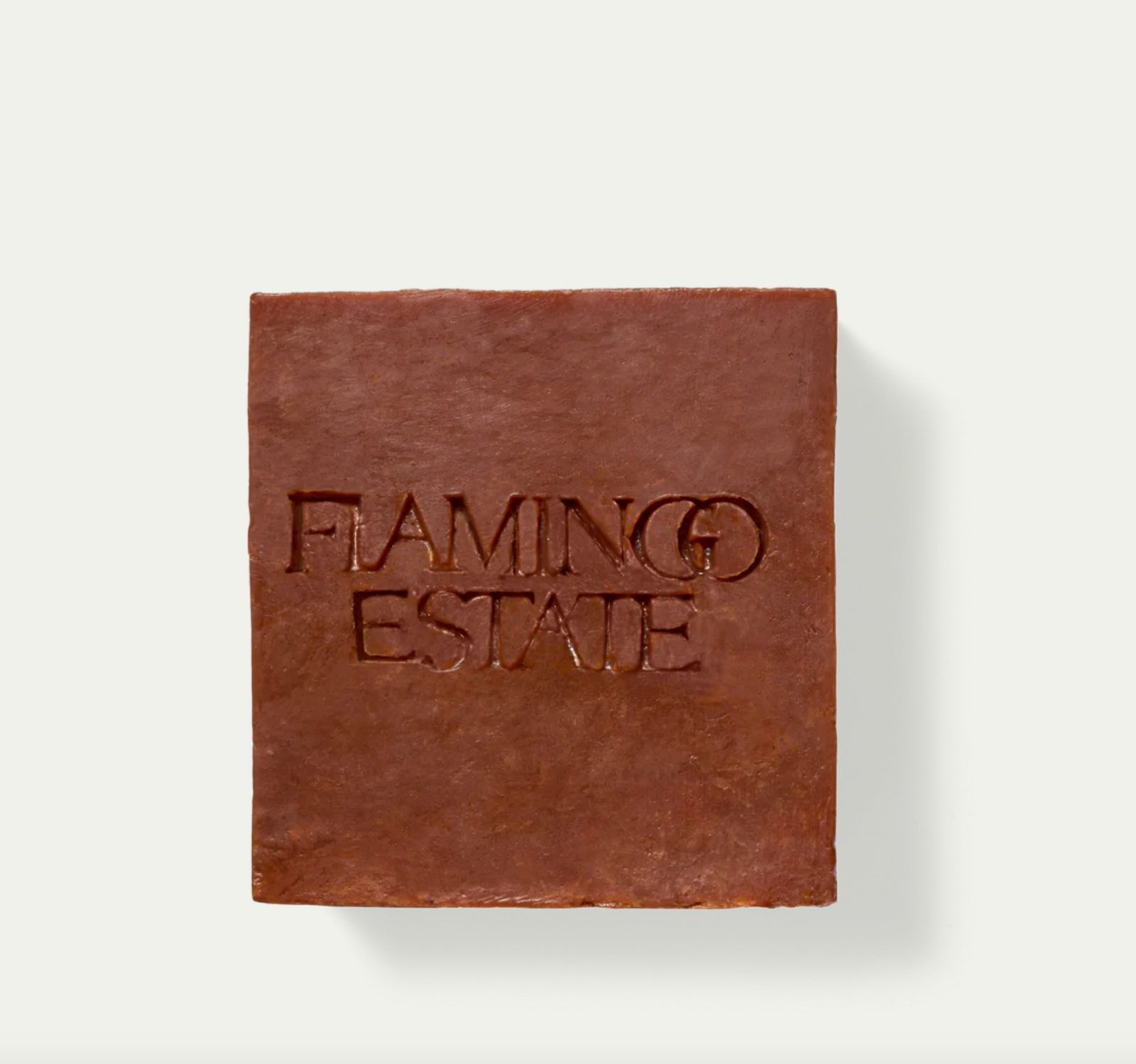 A brown bar of soap with 'FLAMINGO ESTATE' embossed on the top surface, placed on a white background.