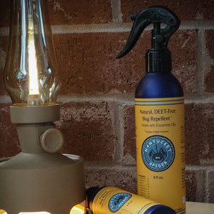 Bug repellent spray bottle with a lamp against a brick wall background