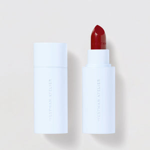 Lipstick with white casing and red shade on a light beige background