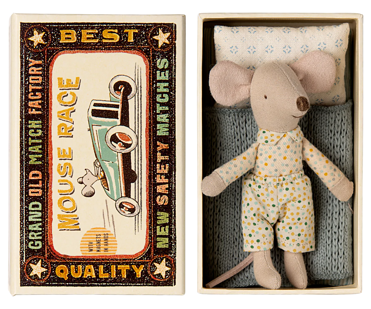 A toy mouse in a matchbox, with the mouse dressed in a pajama set and the matchbox interior featuring a blue and beige design. The matchbox lid has a vintage style with a graphic of a car and the text 'Best Quality'.