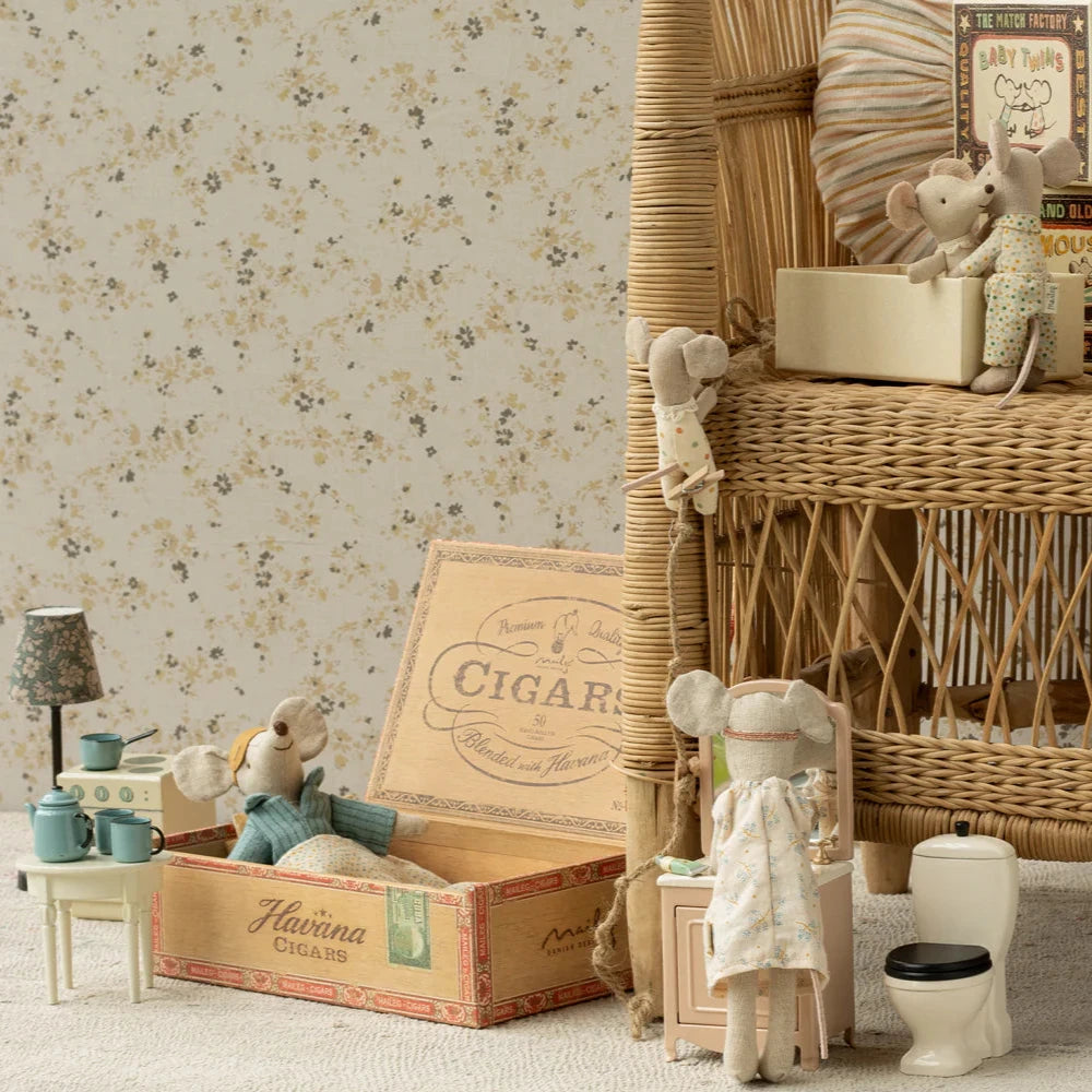 A toy mouse in a matchbox, with the mouse dressed in a pajama set and the matchbox interior featuring a blue and beige design. The matchbox lid has a vintage style with a graphic of a car and the text 'Best Quality'.