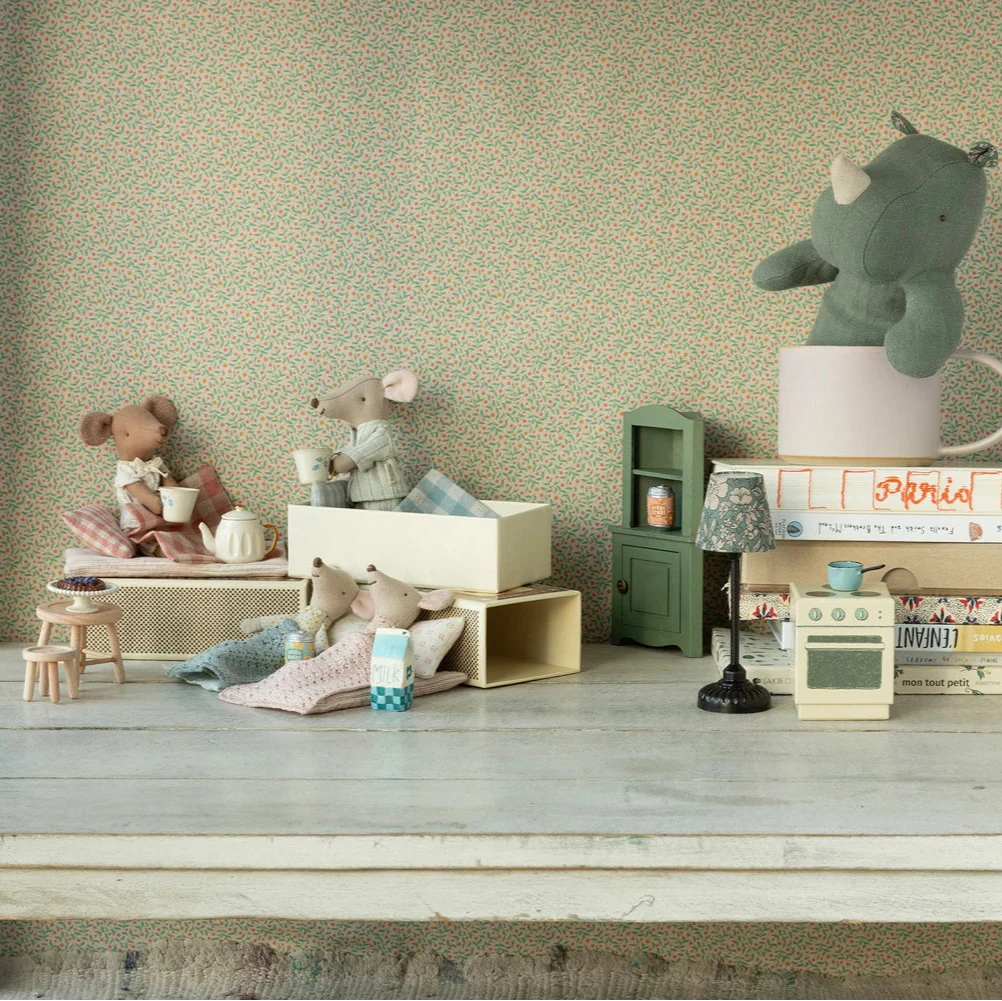 Miniature toys and furniture on a wooden surface with a patterned wall in the background