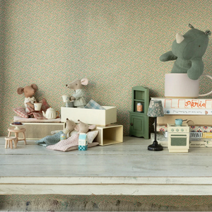 Miniature toys and furniture on a wooden surface with a patterned wall in the background