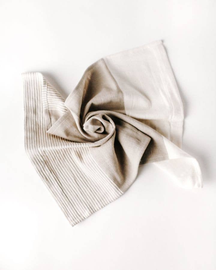 A folded Chesapeake tea towel featuring natural and accented colors with textured stripes, displayed on a white background.