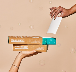 Two boxes of Kind Laundry, with bubbles in the airing a hand. 