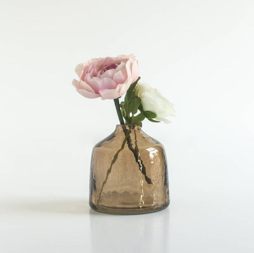 A handblown hammered glass bud vase in brown.