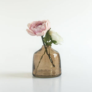 A brown glass bud vase with a pink flower. 
