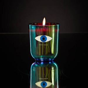Candle in a colorful glass holder with an eye design on a dark background