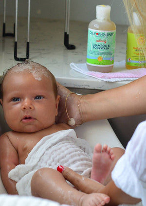 Baby being bathed with a bottle of shampoo and body wash in the background