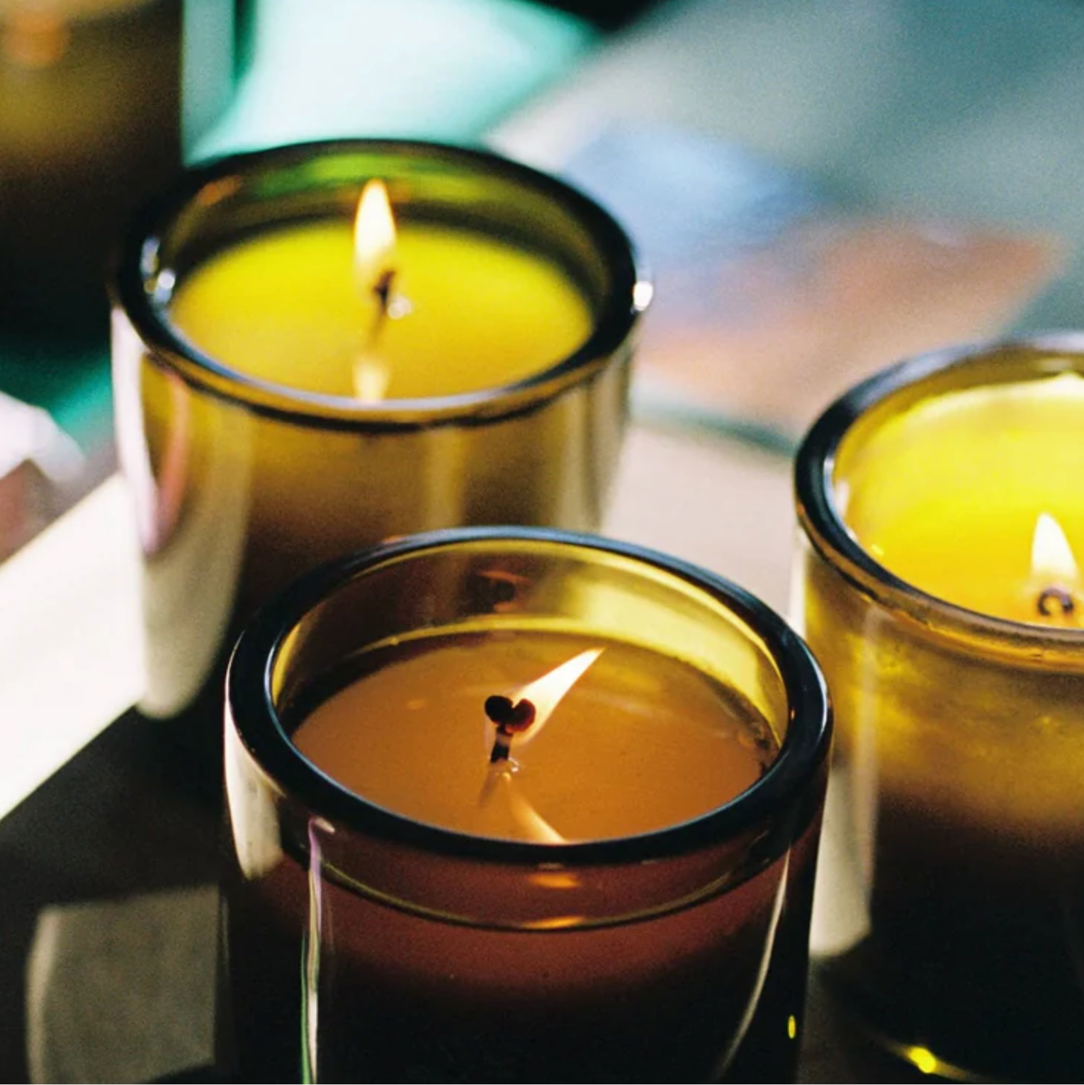 Three lit candles in green glass vessels