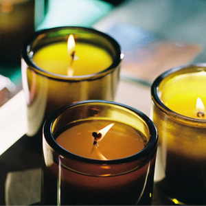 Three lit candles in green glass vessels