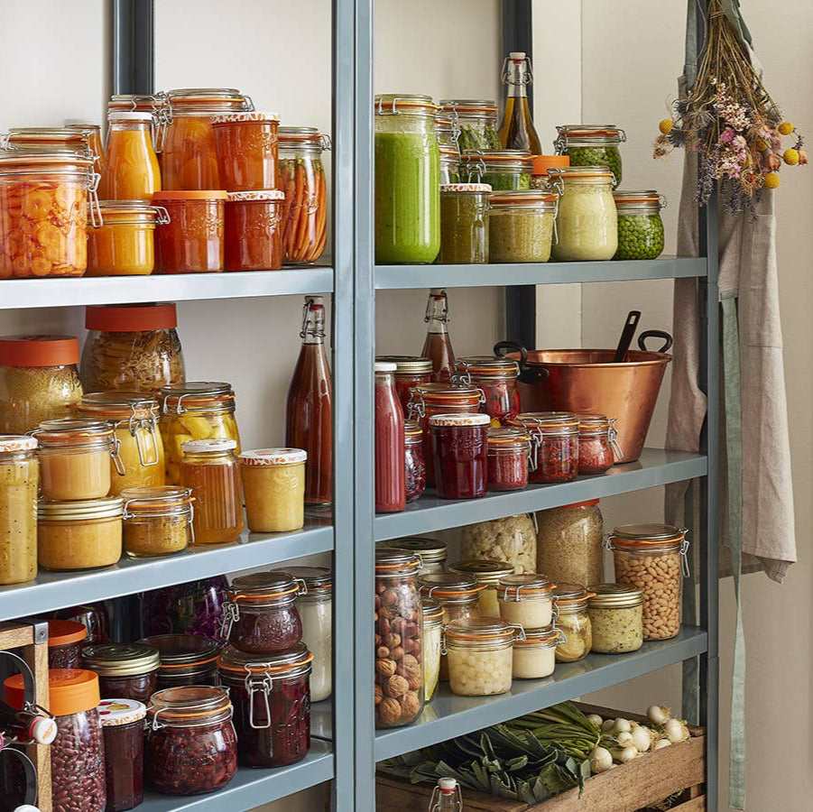 A closet with many glass canning containers filled with fruits and vegetables. 