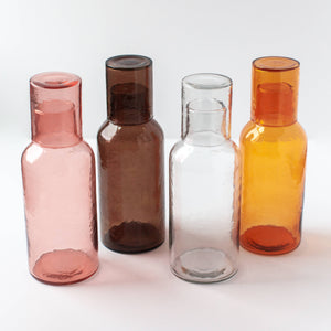 A group of colorful glass carafes on a white background. 
