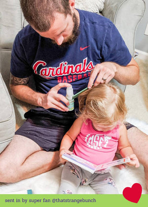 Man applying sunscreen to a child's hair on a couch