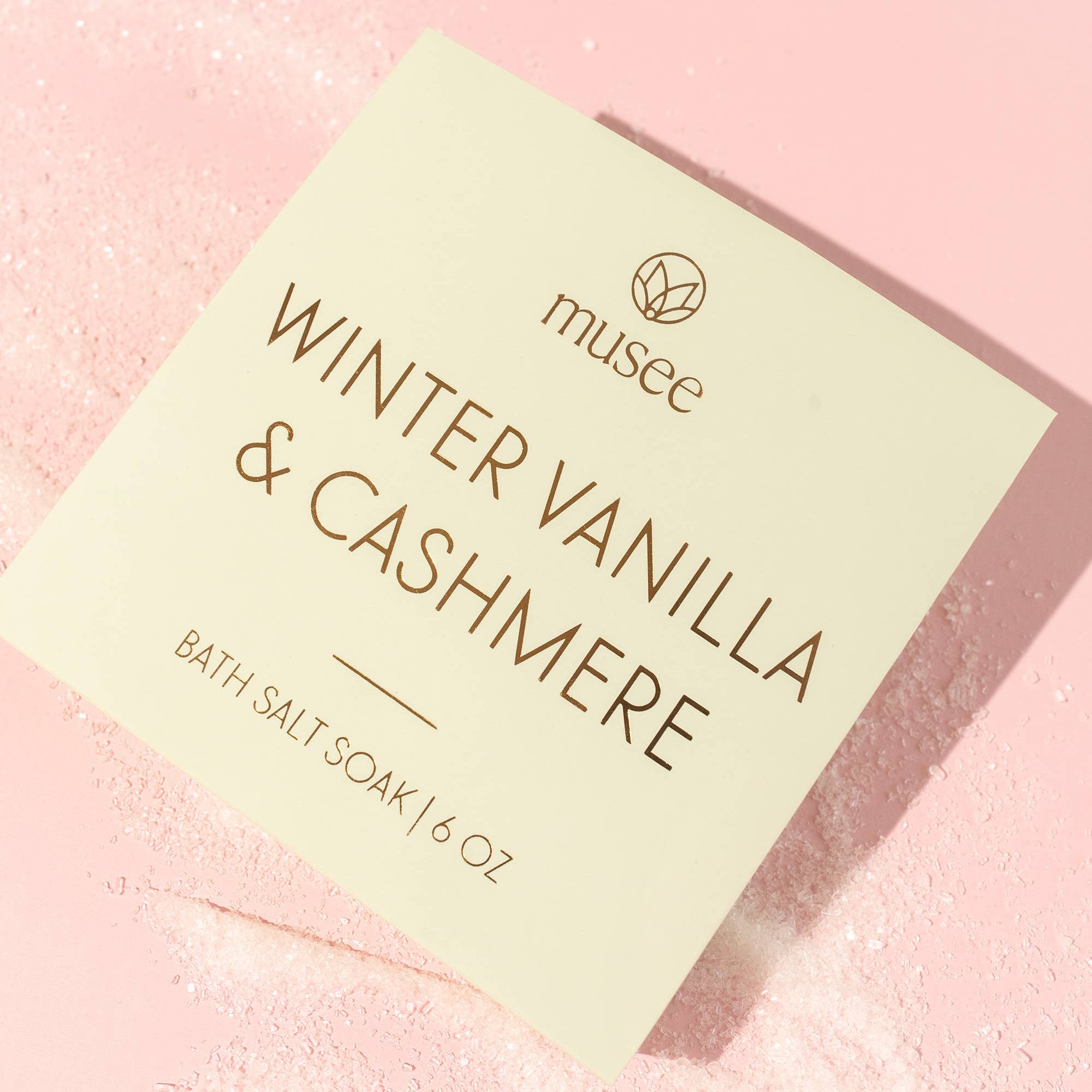 Bath salt soap packaging labeled 'Winter Vanilla & Cashmere' by musee on a pink background