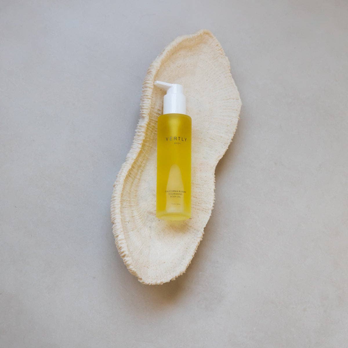 Yellow bottle with pump on a natural beige exfoliating scrub