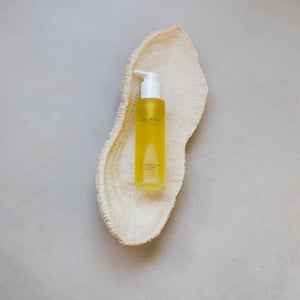 Yellow bottle with pump on a natural beige exfoliating scrub