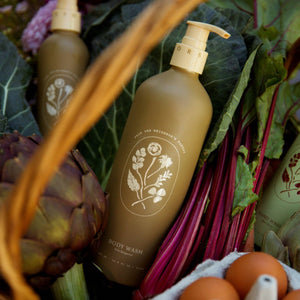 Brown bottles with a logo, eggs, and a basket of vegetables on a wooden surface.