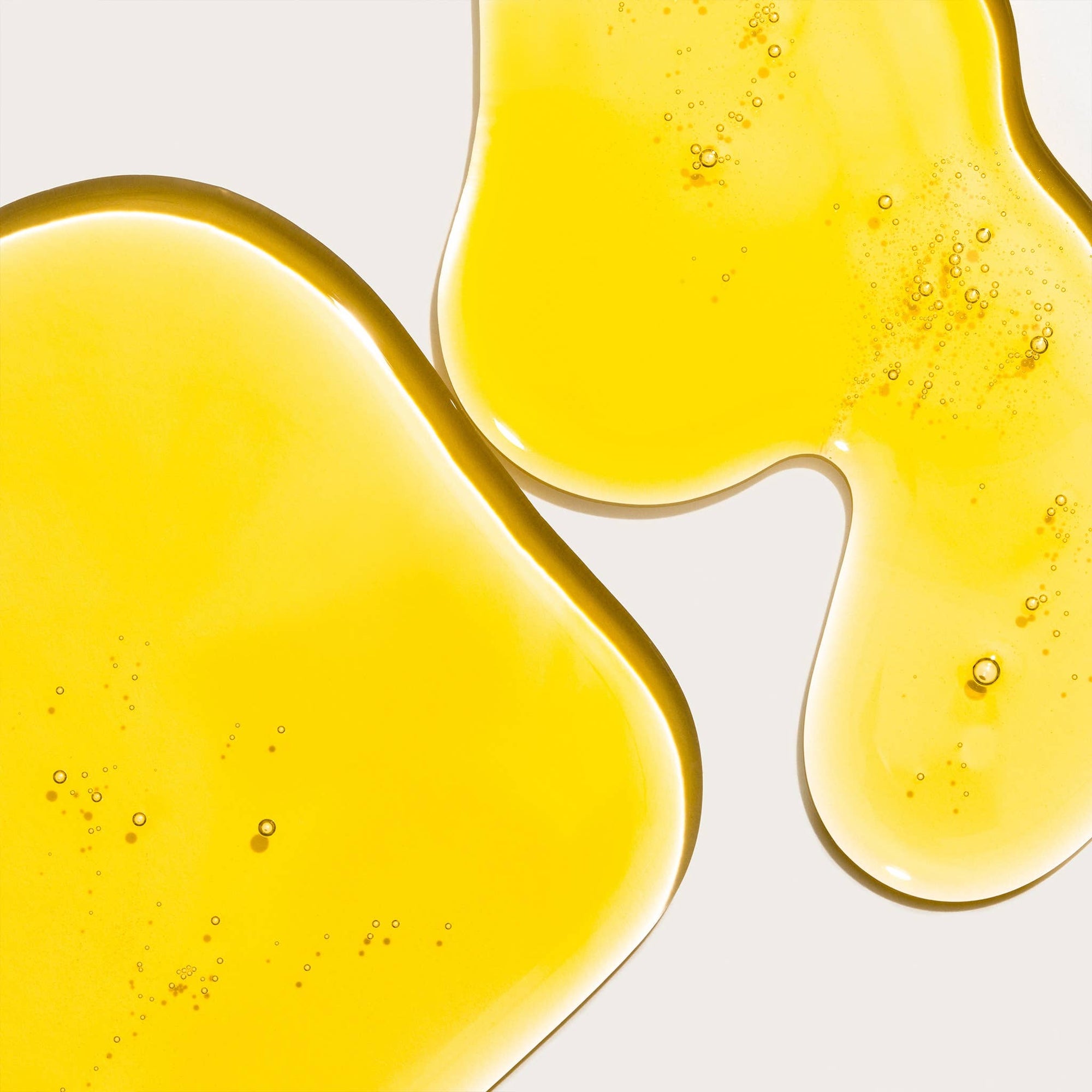 Close-up of yellow liquid with bubbles on a white background