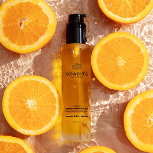 Body oil bottle with oranges on a wet surface