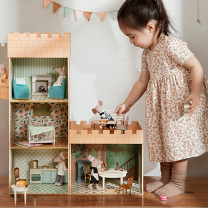 Child playing with a wooden dollhouse set in a room.
