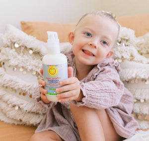 Child holding a bottle of Everyday Lotion with a white background